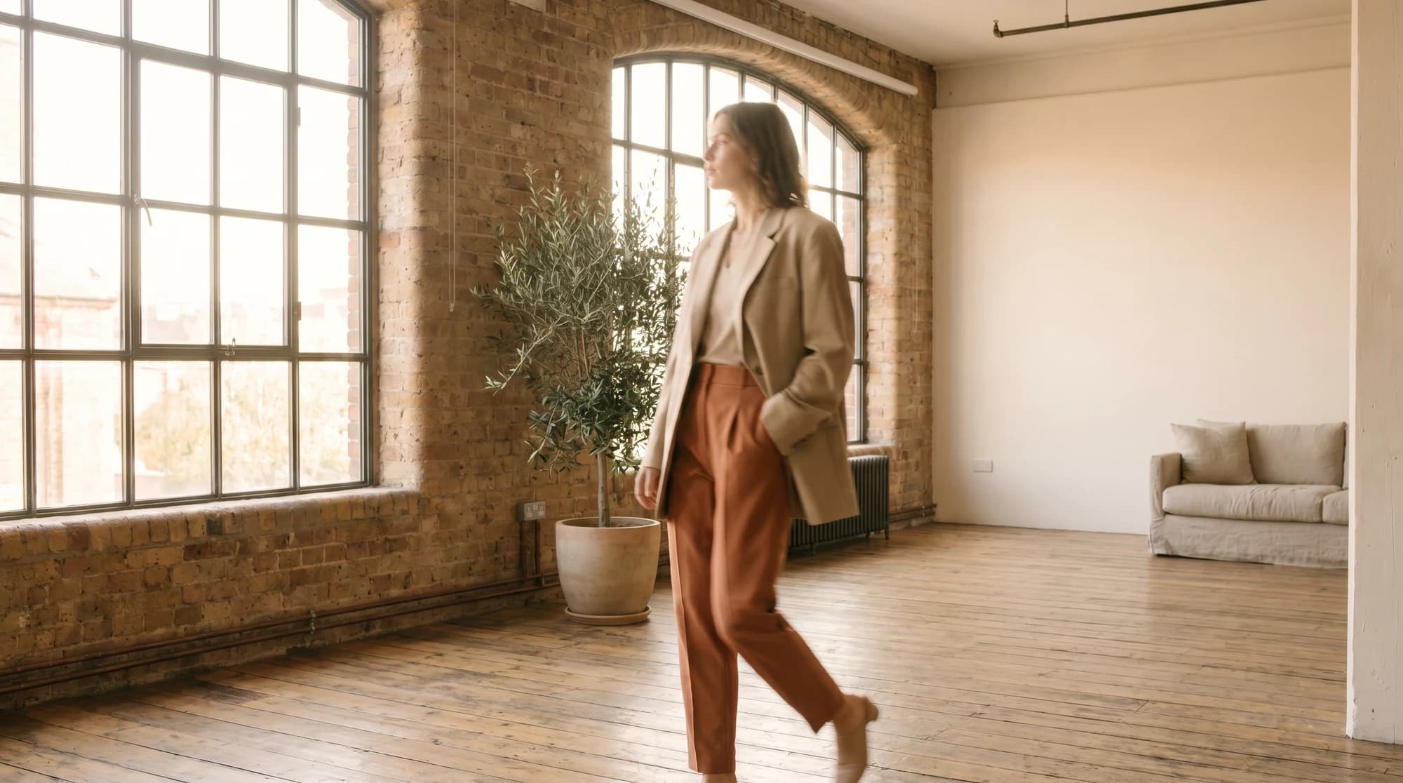 Model in tailored separates walking through a sunlit loft